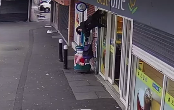 Woman left dangling upside down after coat caught on shop's security shutters