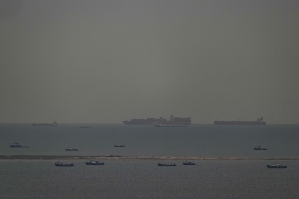 Fishing boats dot the sea as cargo ships, in the background, sail through the Arabian Gulf toward the Strait of Hormuz off the UAE (AP)
