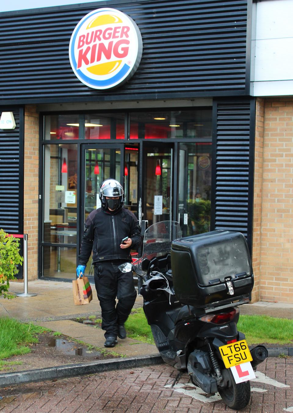 LONDON, ENGLAND  - APRIL 30: A Deliveroo driver collects a food order from a re-opened Burger King restaurant operating on a delivery only basis in the London Borough of Merton on April 30, 2020 in London, United Kingdom. British Prime Minister Boris Johnson, who returned to Downing Street this week after recovering from Covid-19, said the country needed to continue its lockdown measures to avoid a second spike in infections. (Photo by Mark Trowbridge/Getty Images)