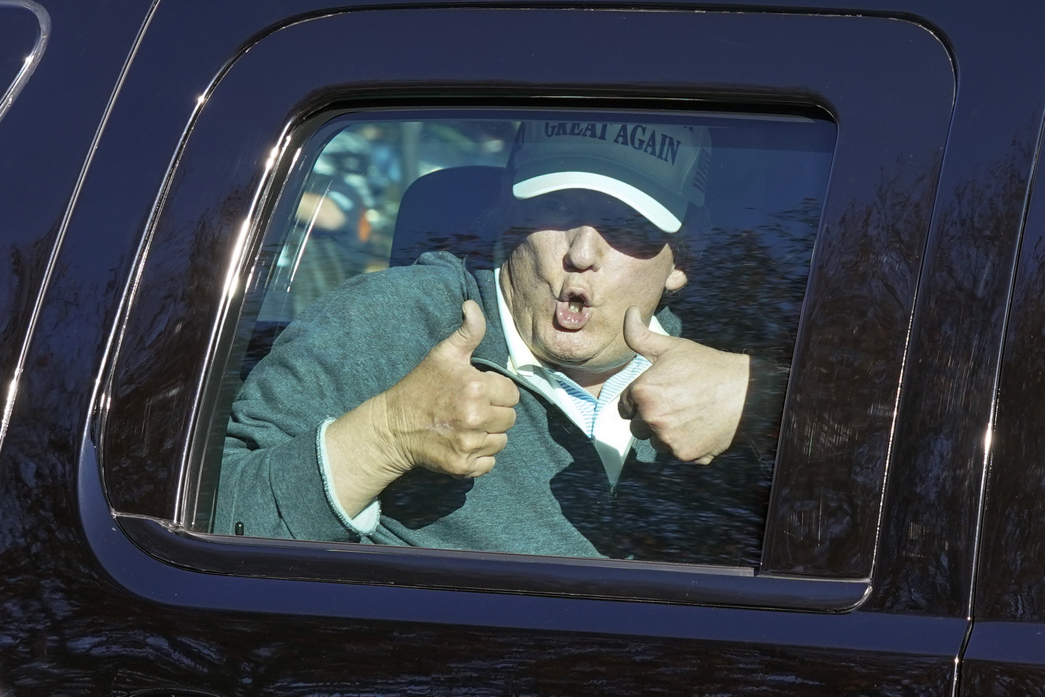 President Donald Trump gives two thumbs up as he departs after playing golf at the Trump National Golf Club