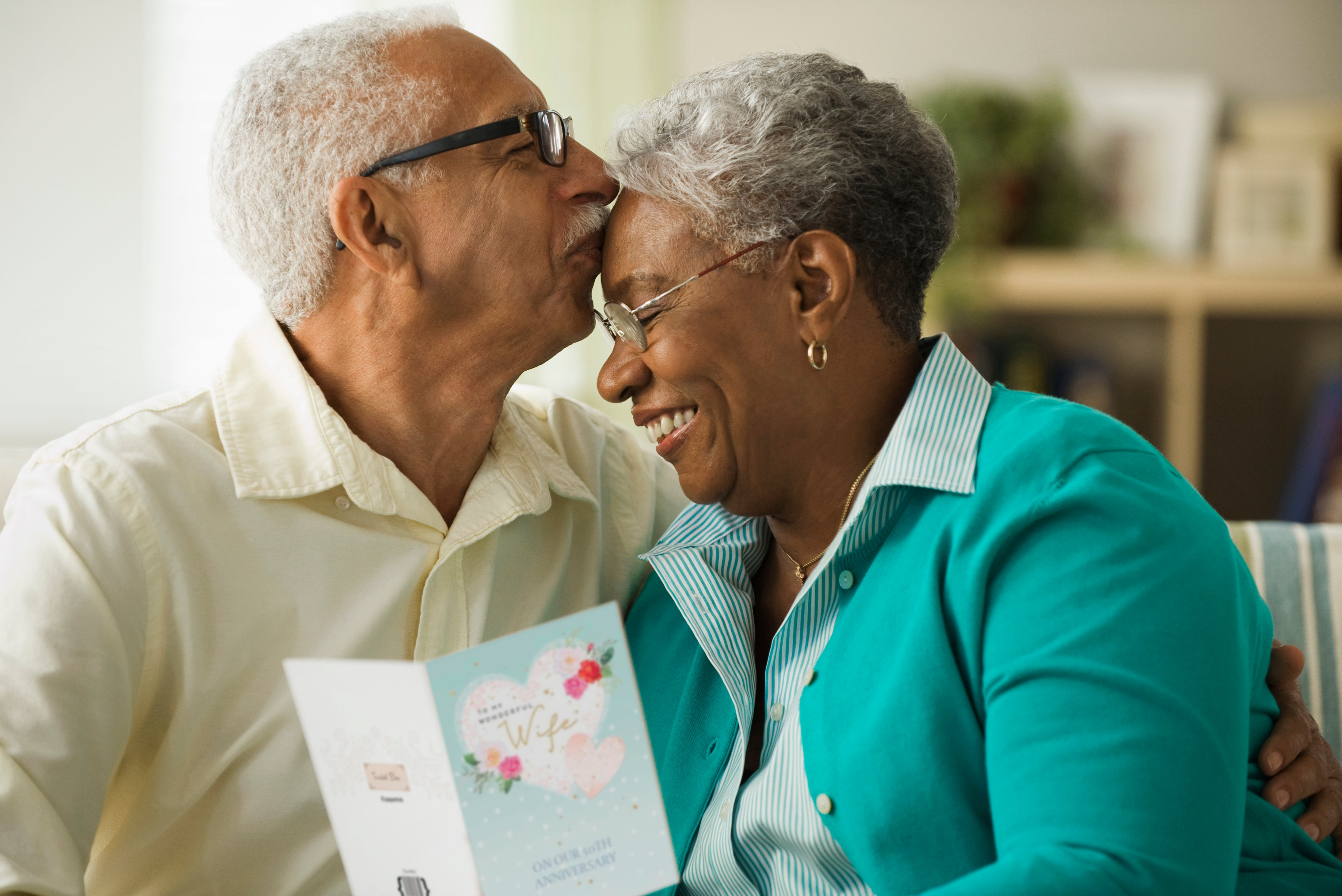 Elderly man kissing wife on the forehead