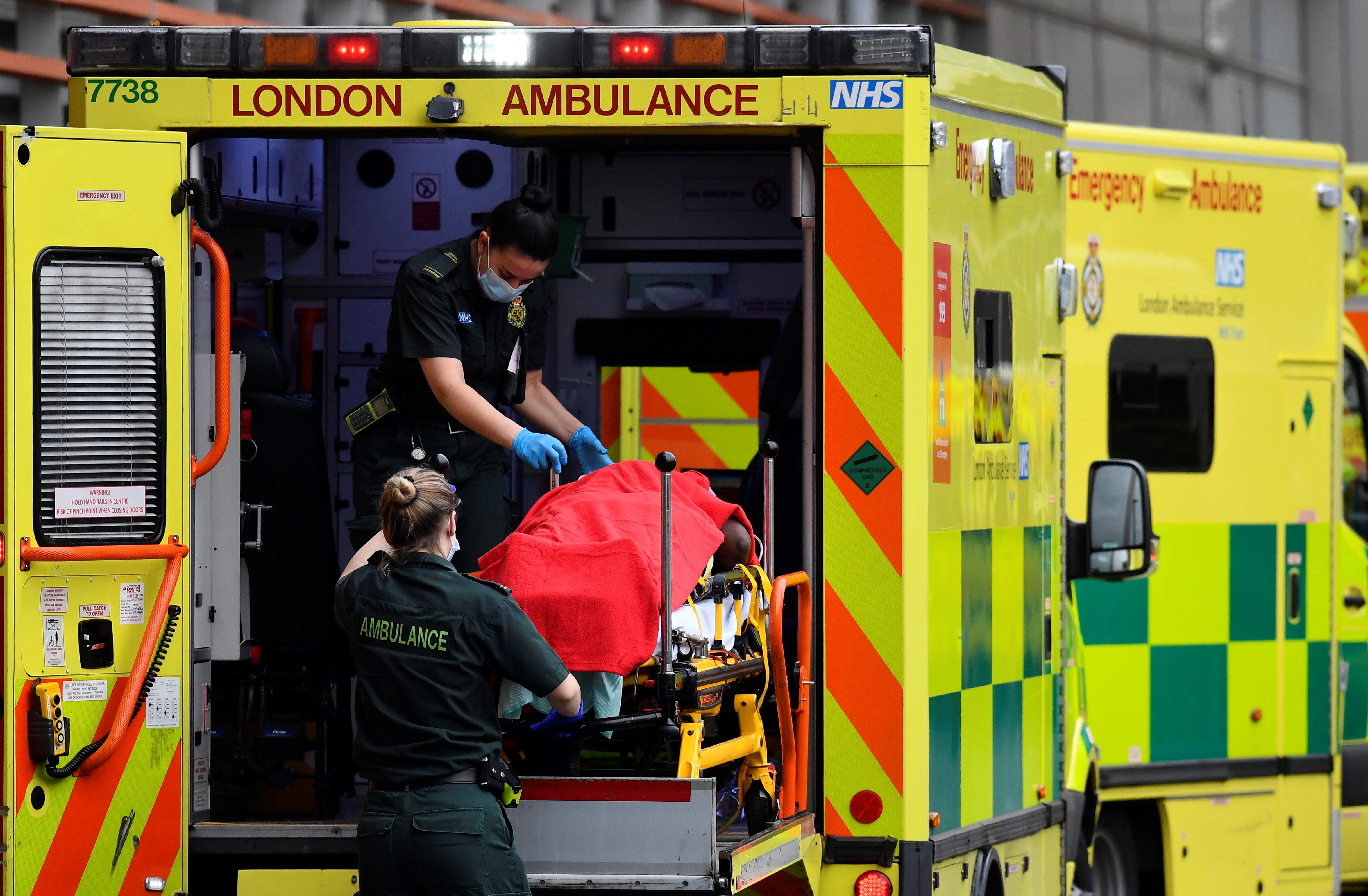 Medical workers bring a patient out of an ambulance, amid the coronavirus disease (COVID-19) pandemic, outside Royal London Hospital