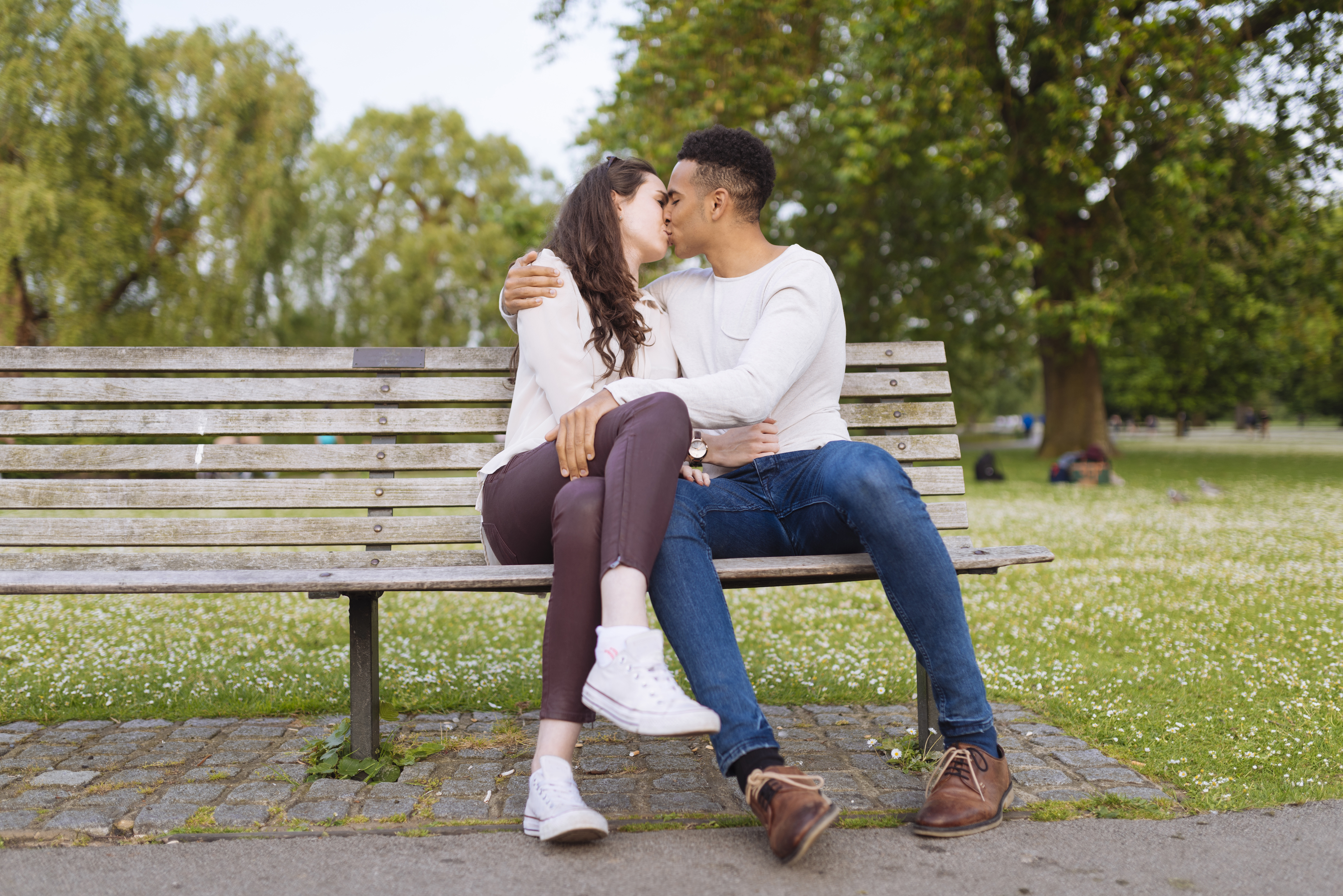 Young couple on park bench kissing