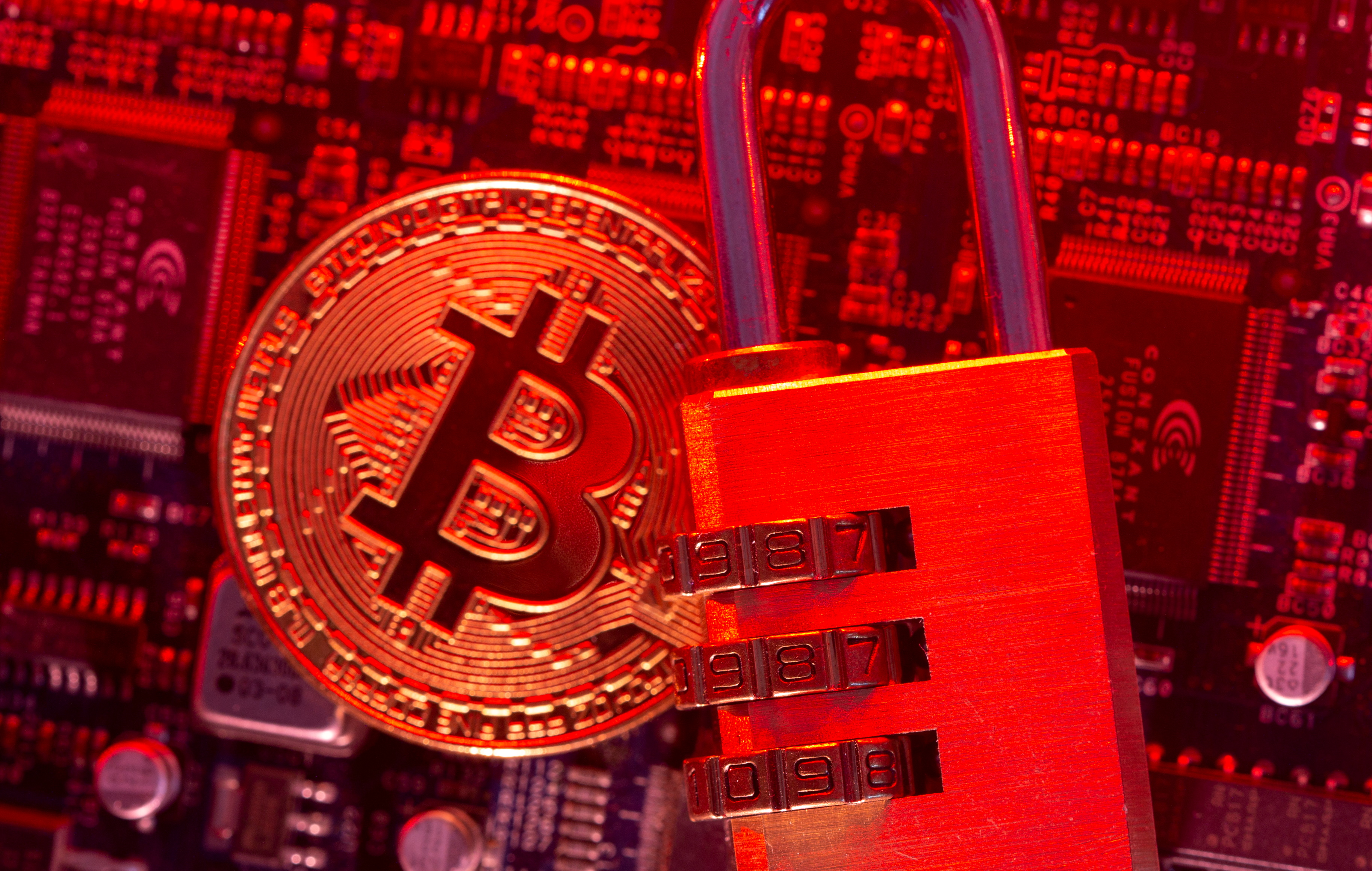 Representation of virtual currency Bitcoin and a padlock on a computer motherboard