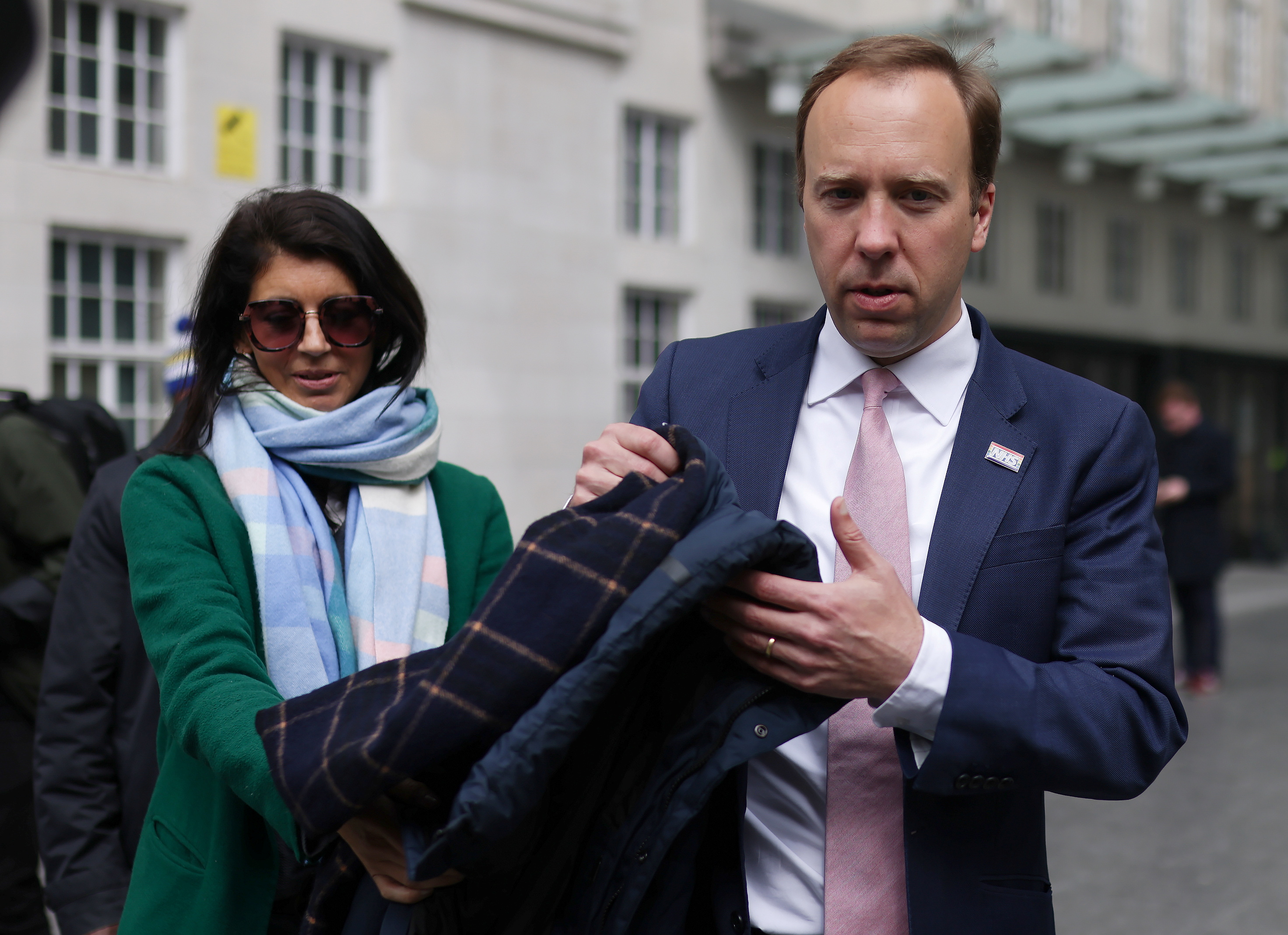Britain's Health Secretary Hancock hands his coat to aide Coladangelo before television interview in London