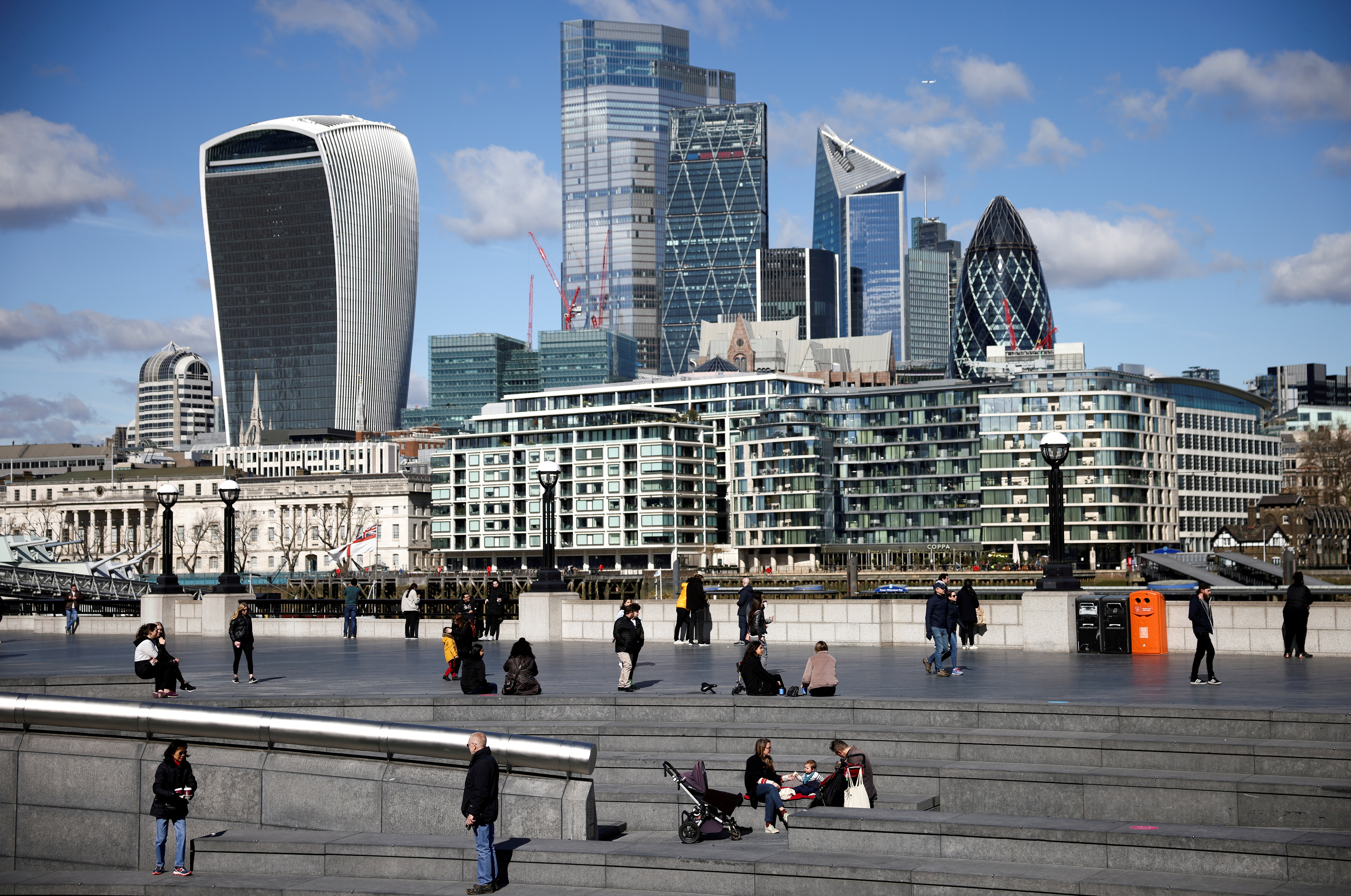 The City of London financial district can be seen as people walk along the south side of the River Thames, amid the coronavirus disease (COVID-19) outbreak in London