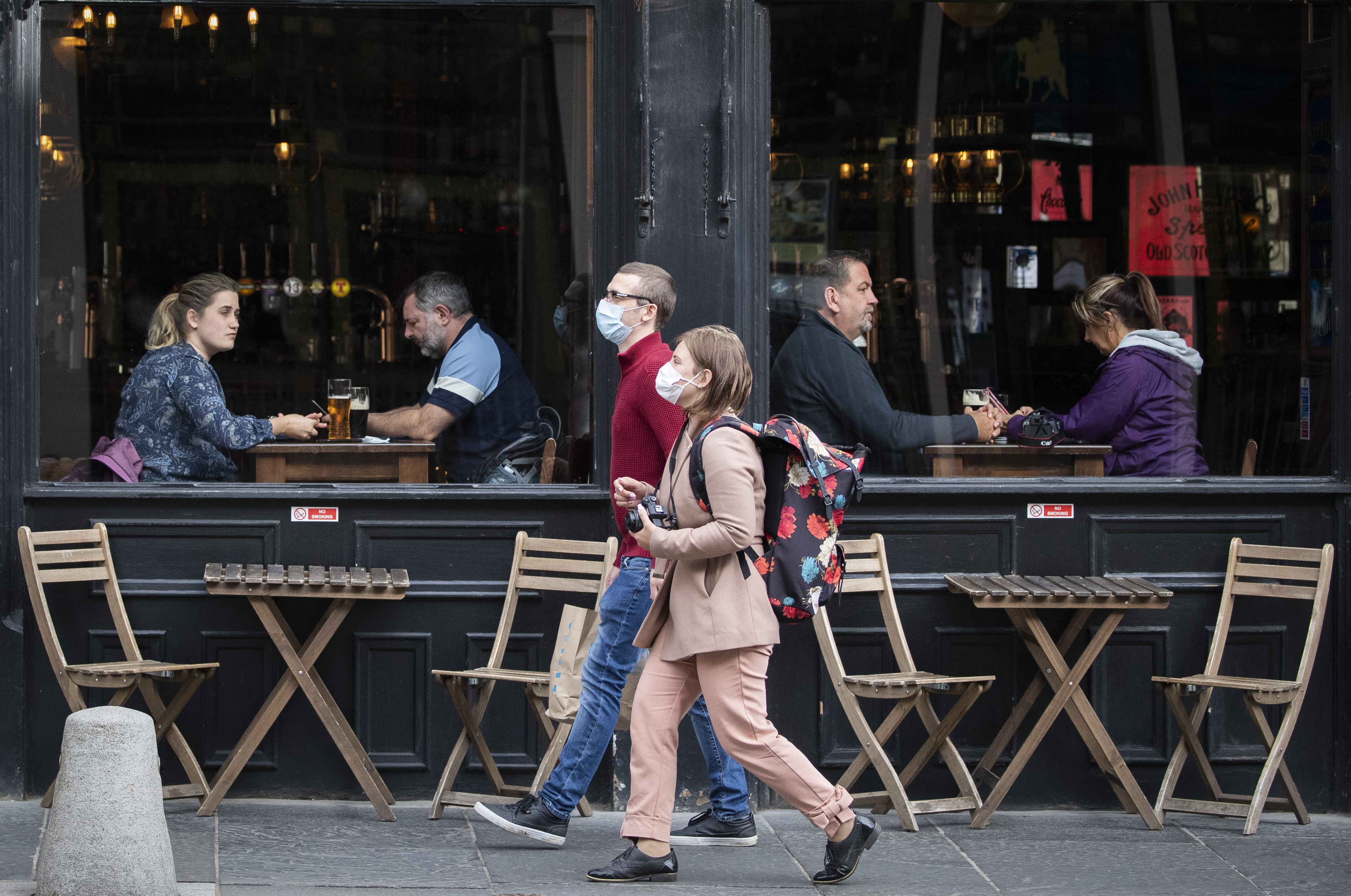 People wearing protective face masks walk past a bar in Edinburgh city centre