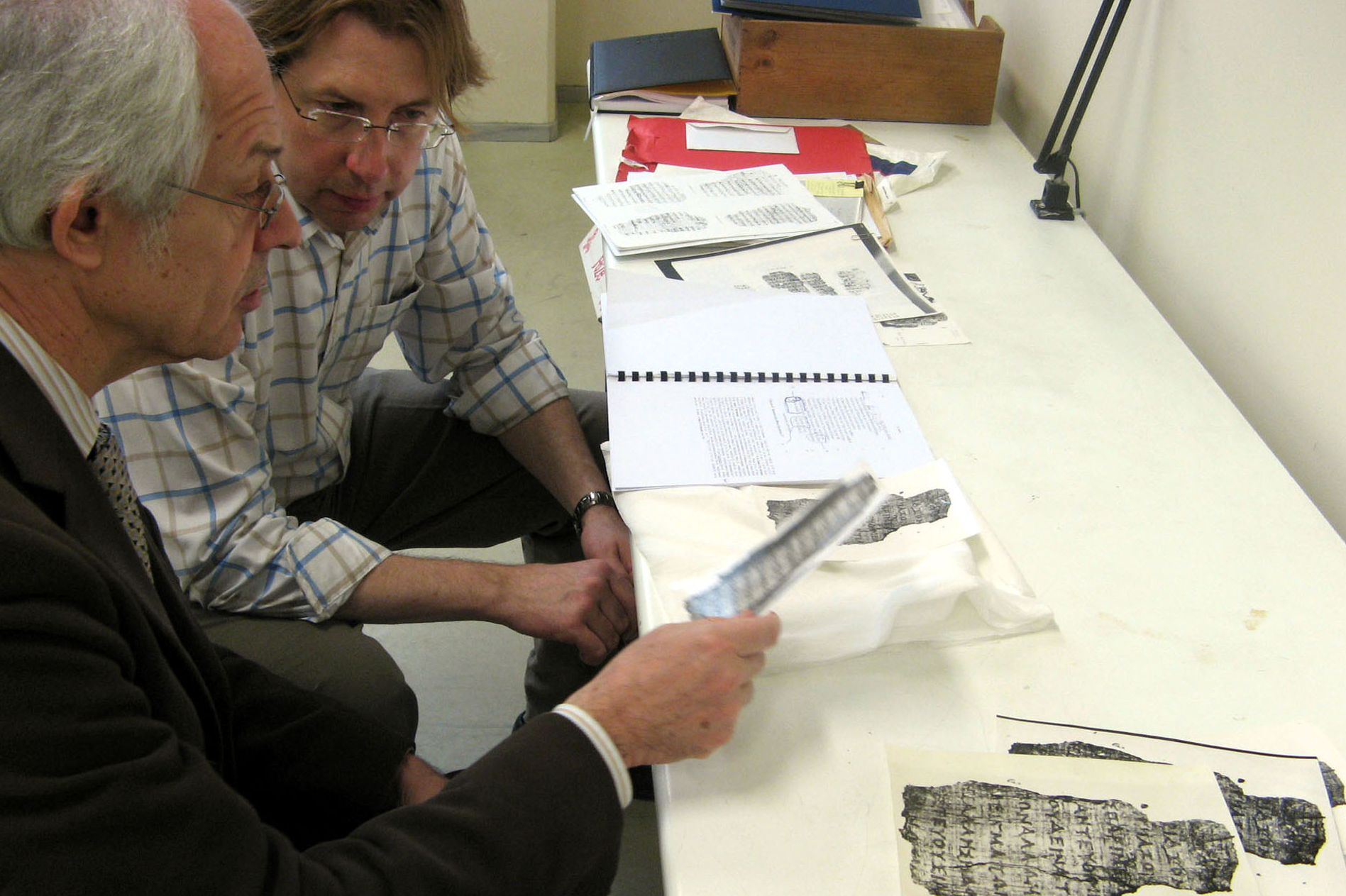 Papyrologist Dirk Obbink, right, and Greece’s Apostolos Pierris examines facsimilie images of a 2,400-year old scroll in Thessaloniki, Greece
