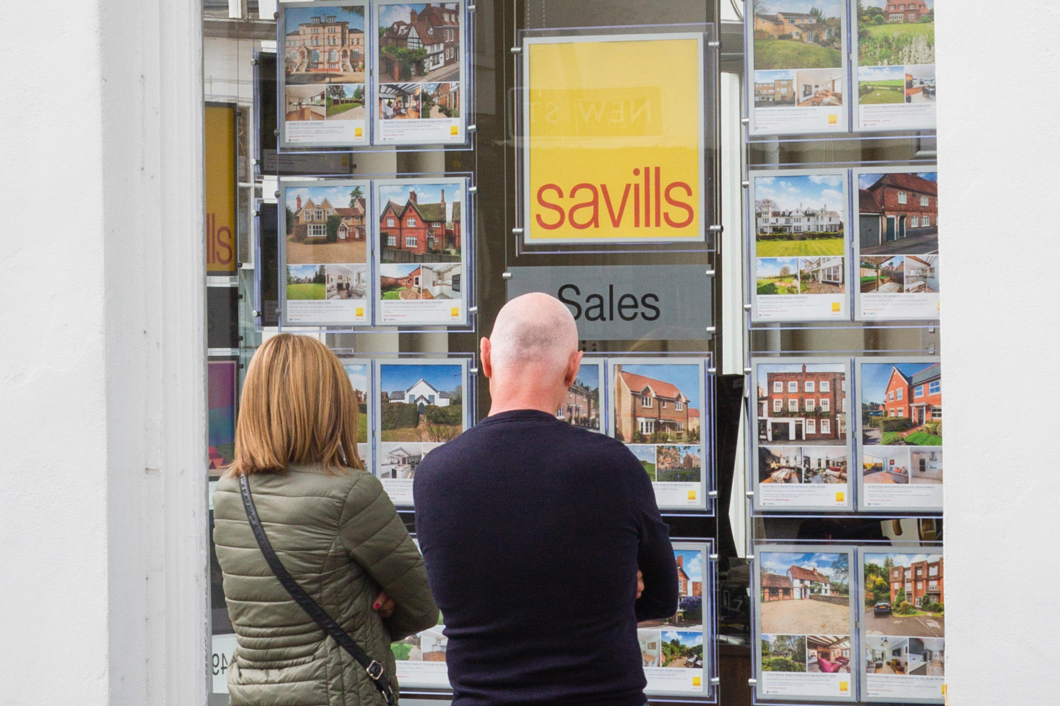 A couple look in the window of Savills estate agents in Henley-on-Thames