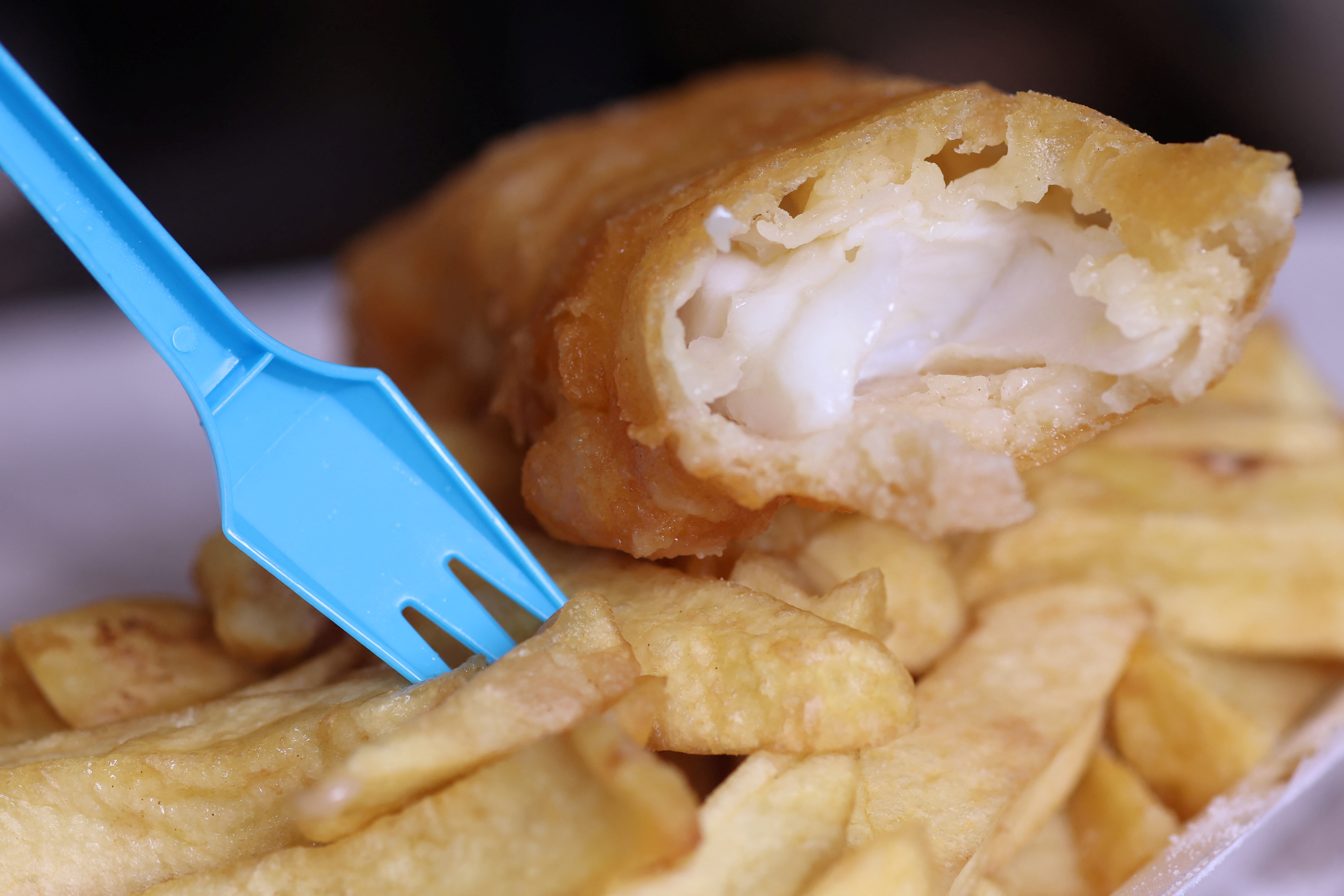 A plastic fork stands in a portion of fish and chips from a fish and chip shop is pictured in Manchester