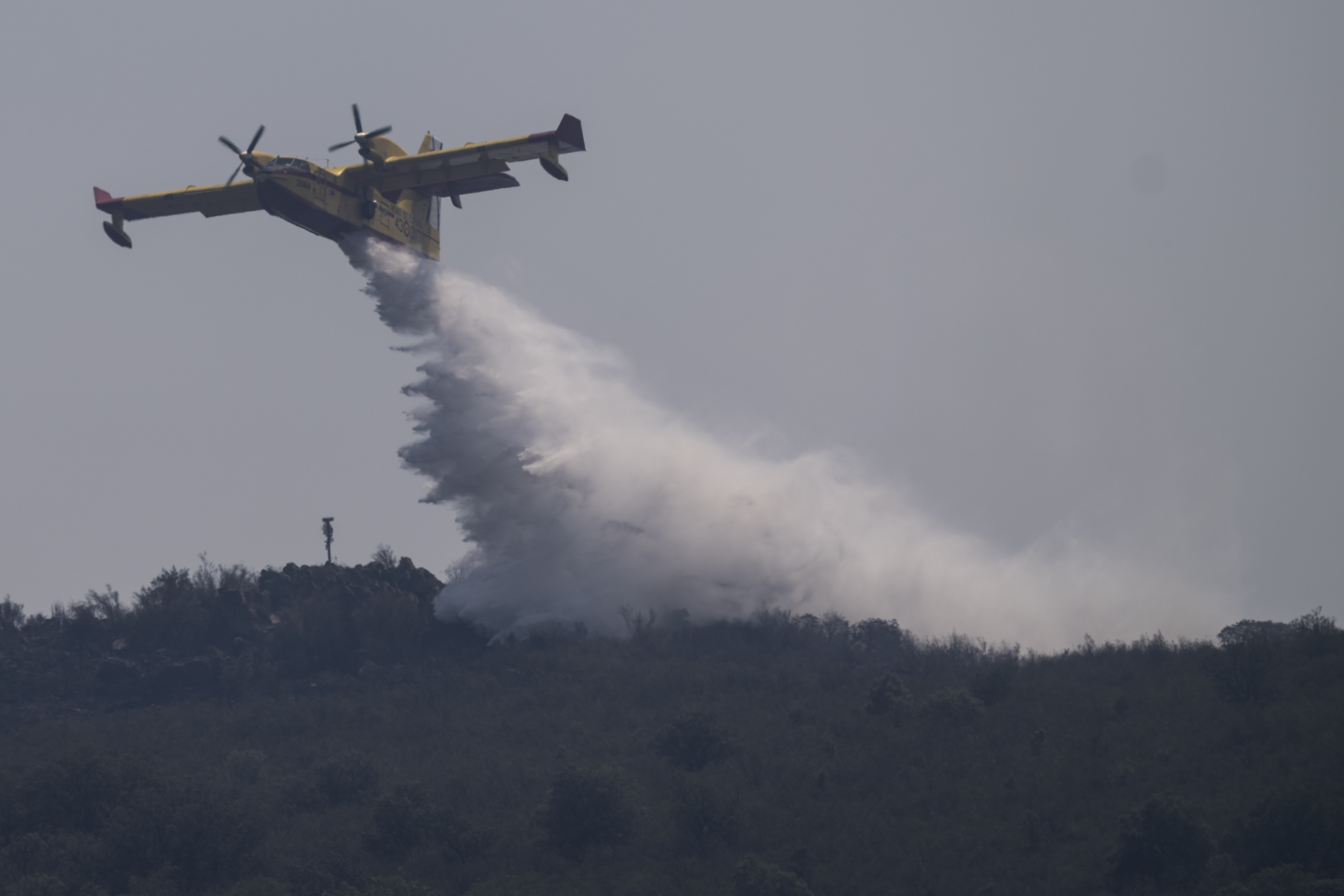 A firefighting plane drops water during fire extinguish works near Tabara, north-west Spain