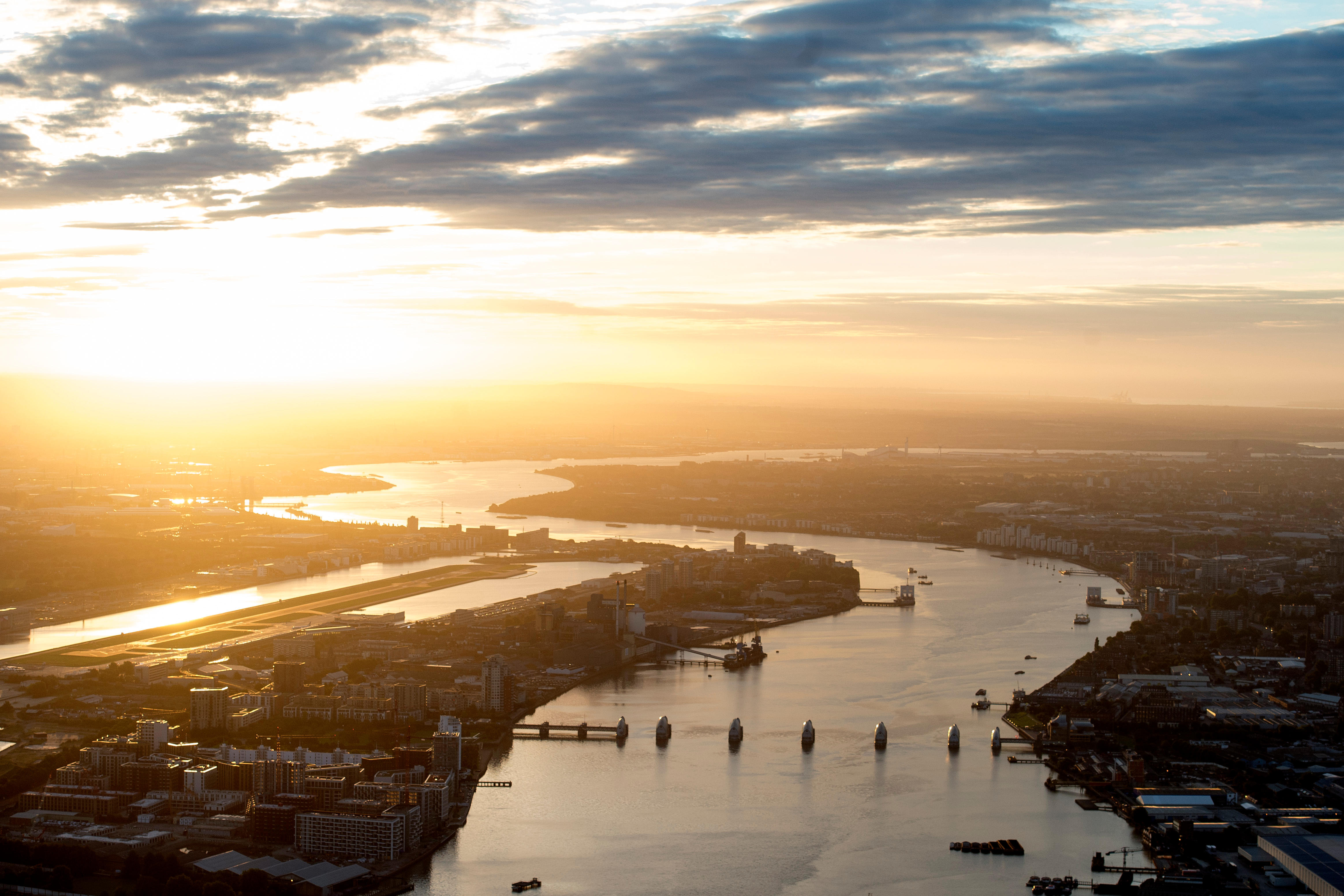 An aerial view of the Thames estuary, including the Thames Barrier, during sunrise.