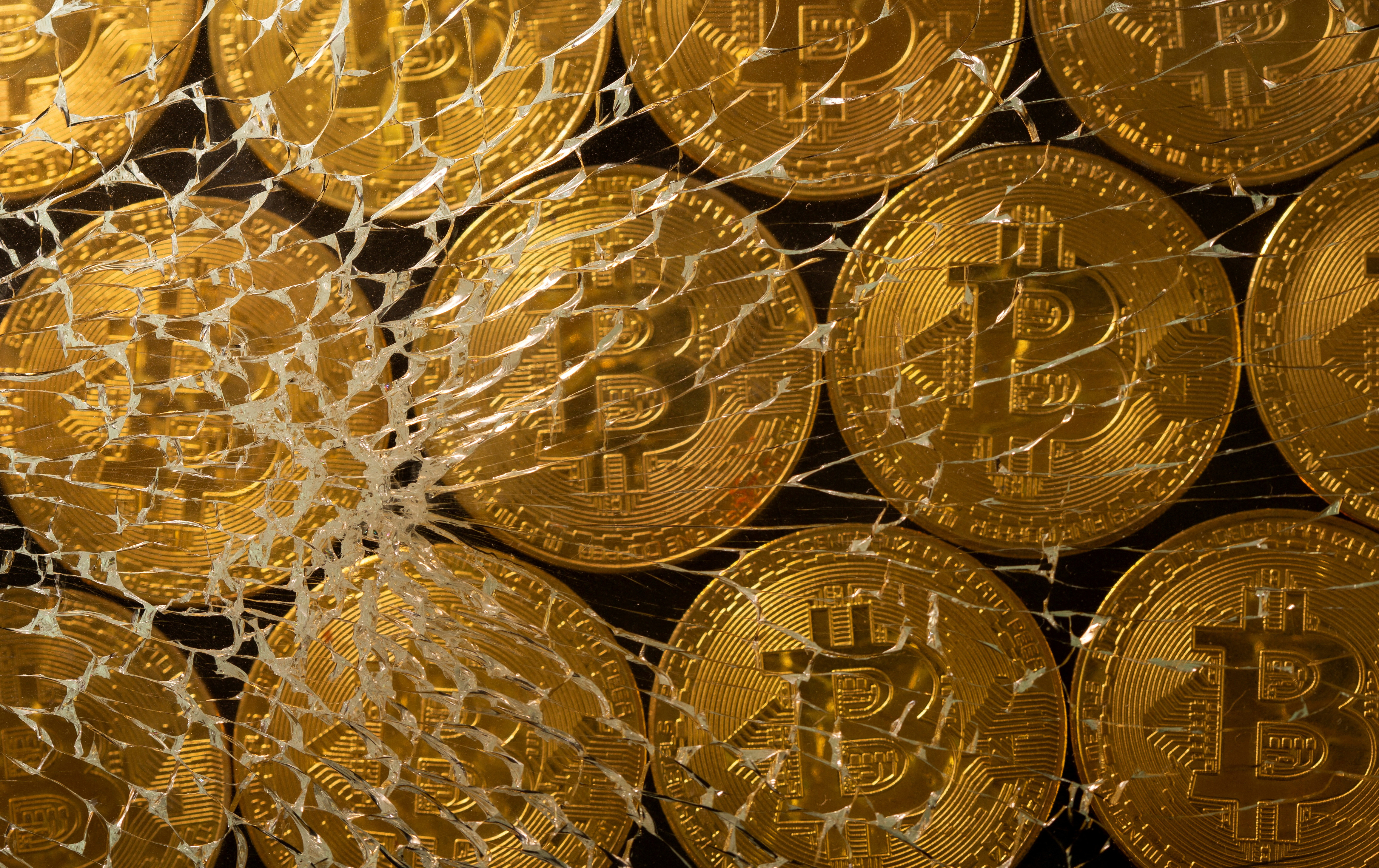 FILE PHOTO: Representations of virtual currency bitcoin are seen through broken glass in this illustration taken
