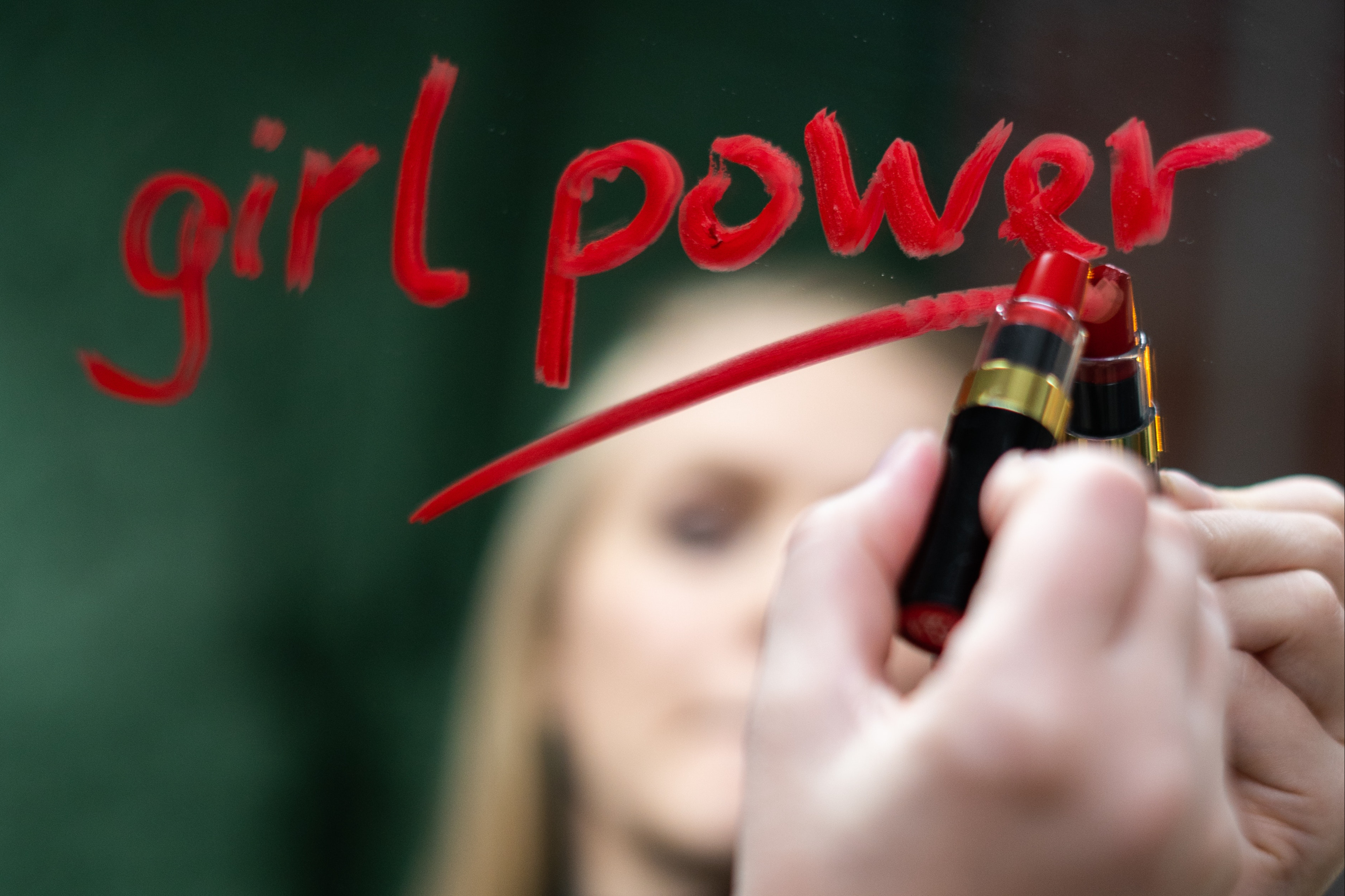 Women writing “girl power” on the mirror with a lipstick
