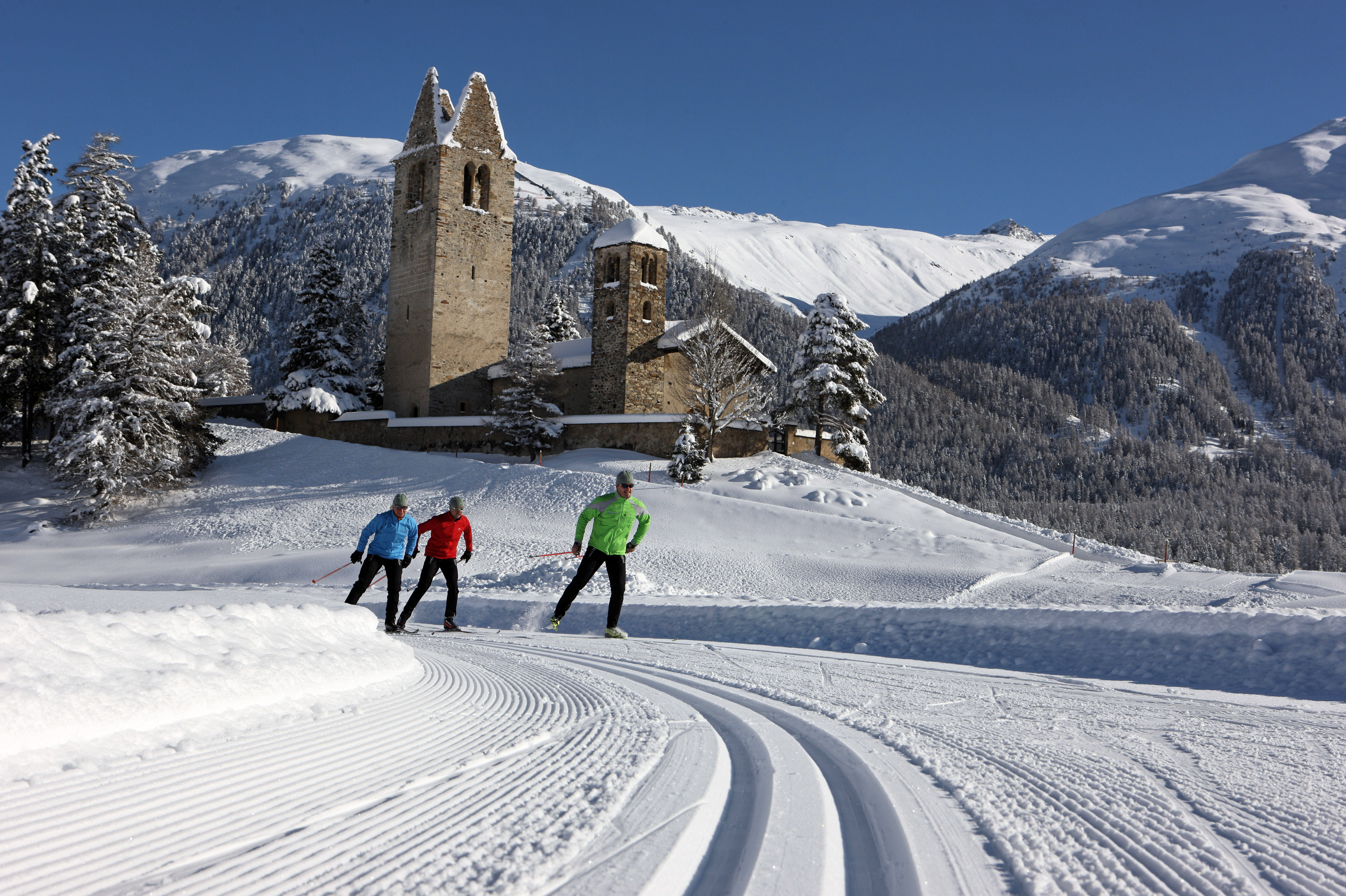 ENGADIN St. Moritz: Langlaeufer vor der Kirche San Gian
