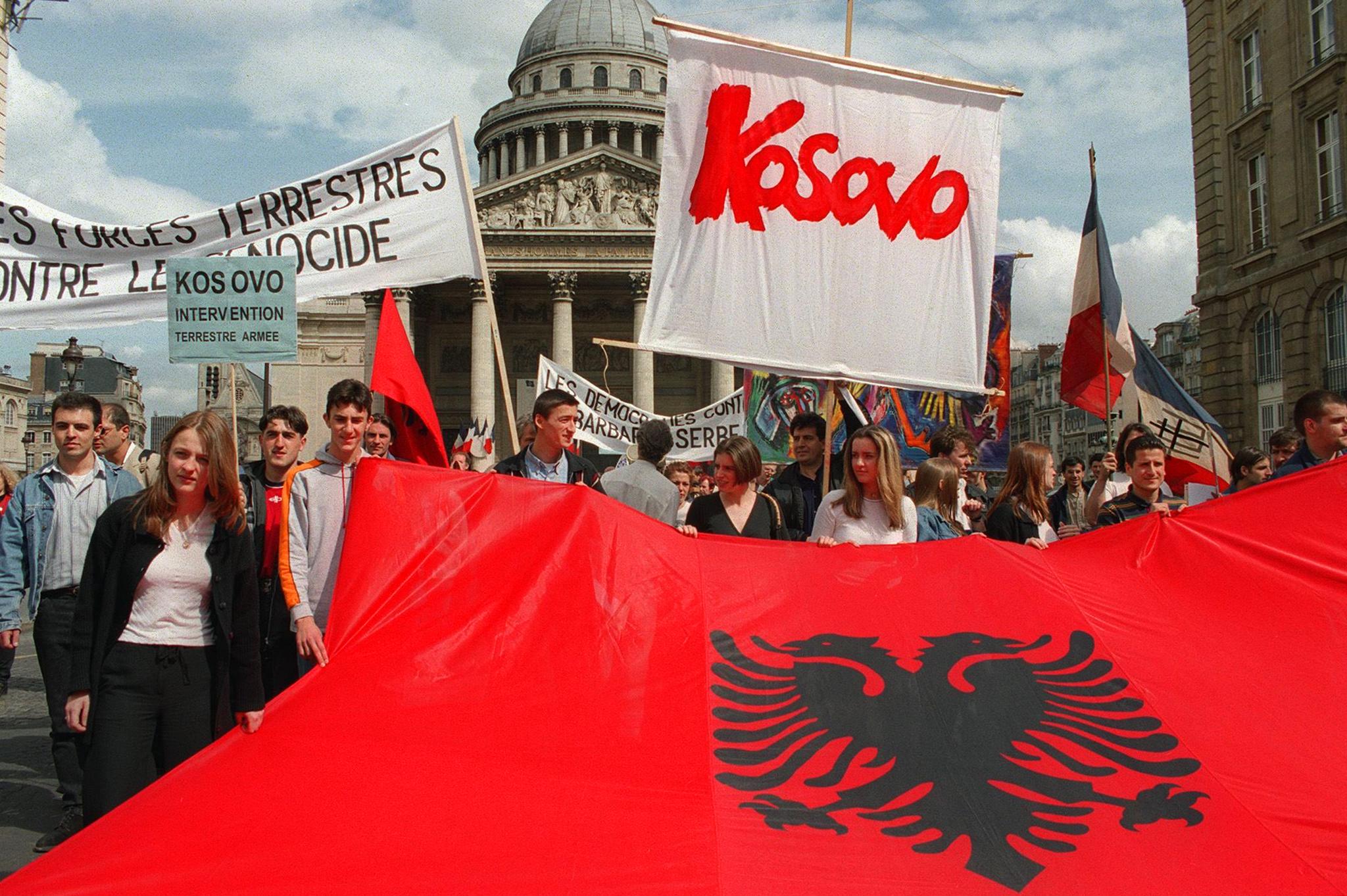 People carry an Albanian flag as they demonstrate in Paris 