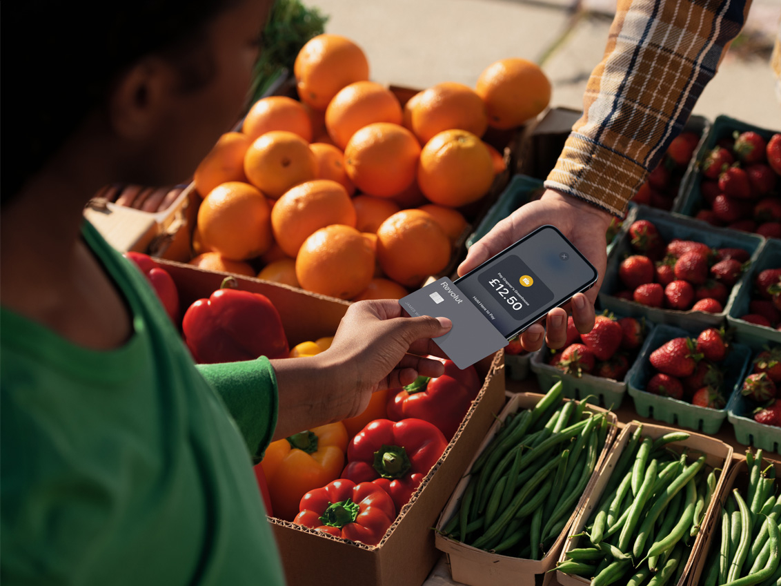 A woman uses Tap to Pay on iPhone to make a contactless payment to a fruit seller