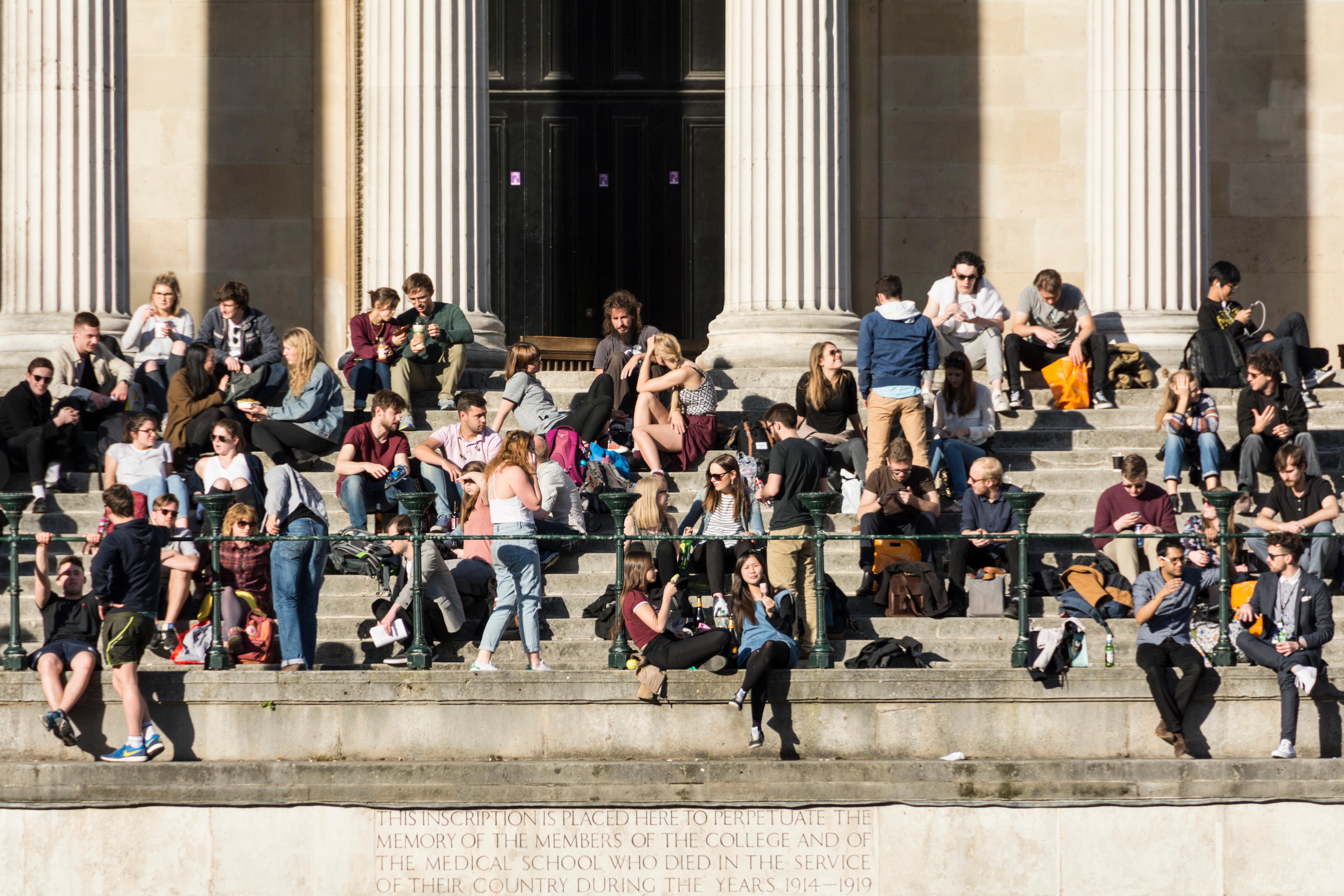 Students sitting on the steps of the Portico and Quad at University College London (UCL), Bloomsbury, London, England, UK