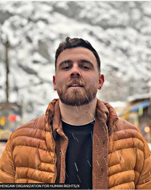 Photo of white man with brown ginger beard outside in the snow wearing an orange puffer coat