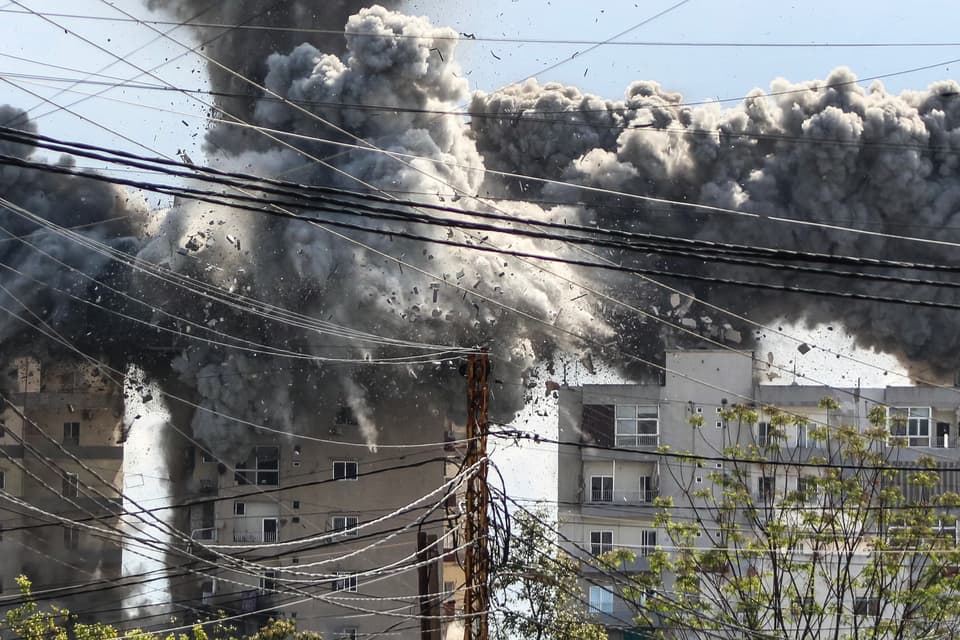 TOPSHOT - Smoke and debris rise after a building is hit by an Israeli airstrike in the area of Abbasiyeh, on the outskirts of the southern Lebanese city of Tyre, on April 8, 2026. Lebanon's army warned people against returning to the country's south on April 8, where the Israeli military is still launching attacks, as Israel said the ceasefire with Iran did not include its conflict with Hezbollah. (Photo by Kawnat HAJU / AFP via Getty Images)