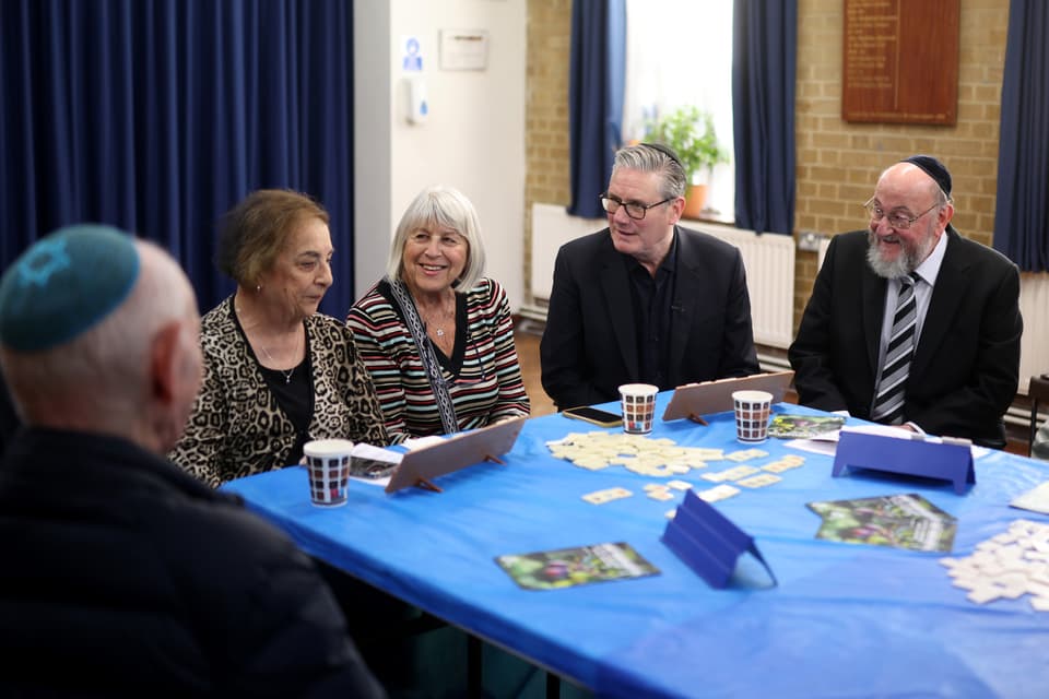 <p>Sir Keir Starmer, sitting next to Chief Rabbi Ephraim Mirvis. speaks to people during a visit to Kenton United Synagogue, which was recently the target of an attempted arson</p>