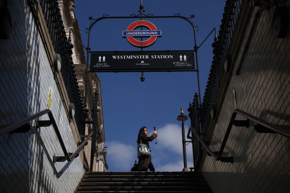  woman walks past the entrance to Westminster Underground Station on April 21, 2026
