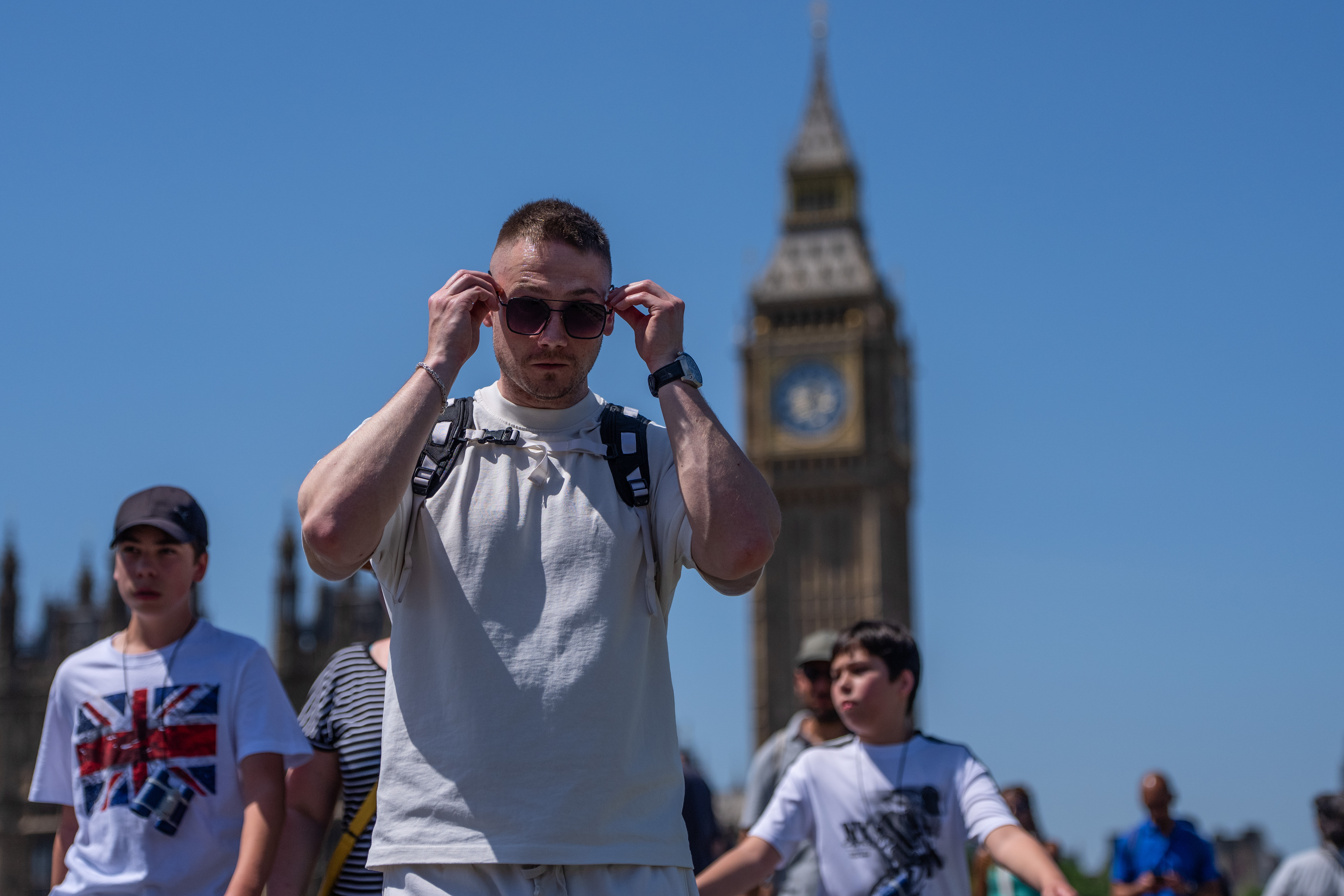 A man puts on his sunglasses as he walks over Westminster Bridge with his family on May 26, 2026